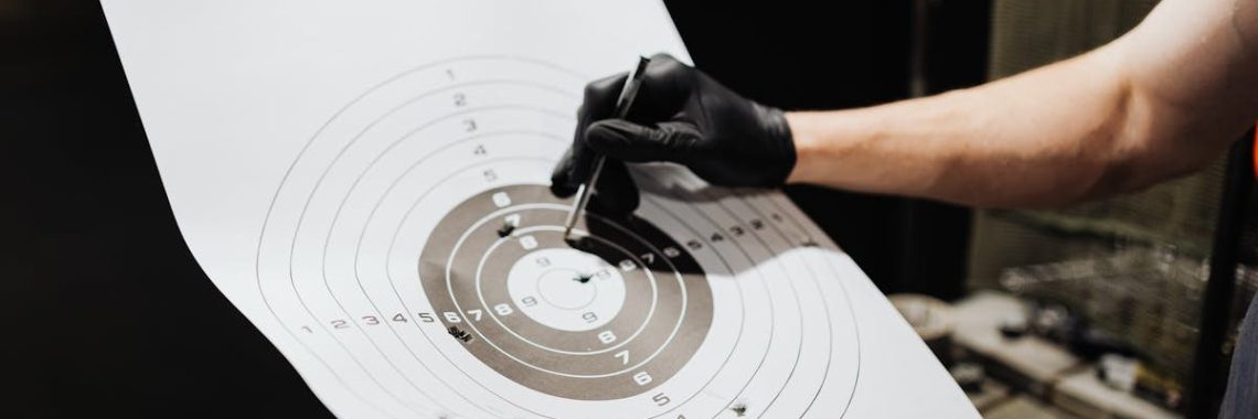 Close-up of a person marking hits on a shooting range target with a marker.